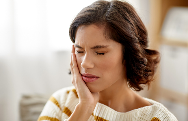 Brunette woman holding the side of her face in pain
