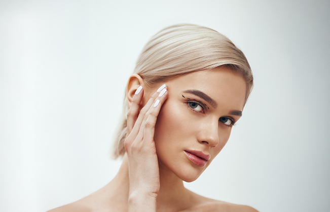 Woman with flawlessly smooth skin touching her face