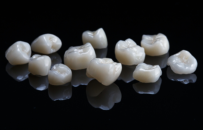 Several tooth colored dental crowns against a black background