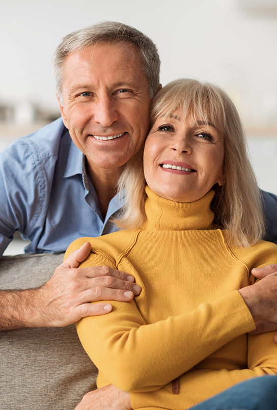 Older couple smiling after replacing missing teeth in Maple Valley