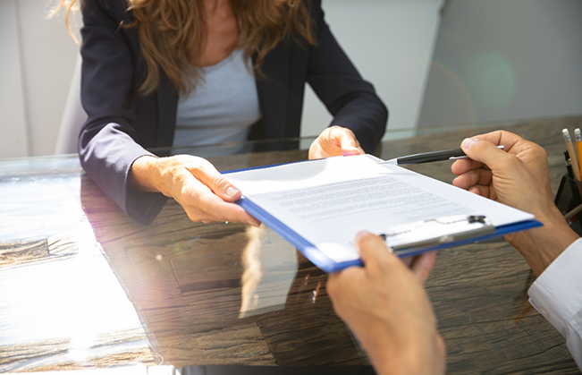 Dental tema member handing a clipboard with forms to a patient