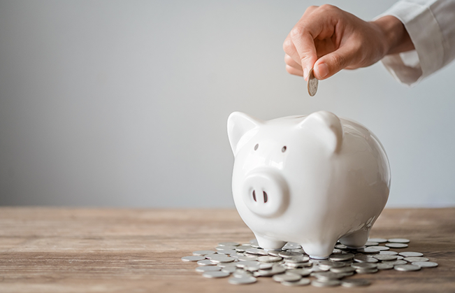 Person putting a coin into a piggy bank