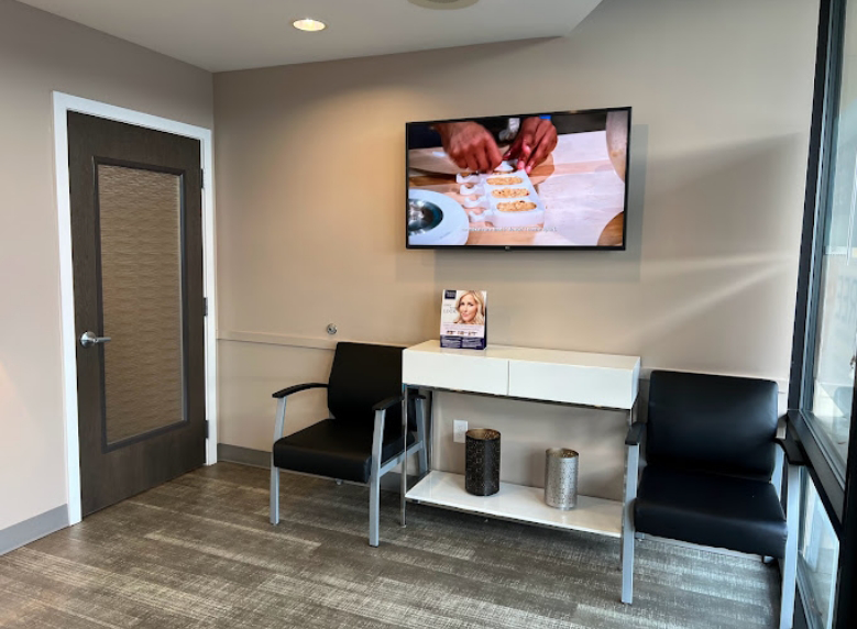 Two chairs in the waiting area with a TV on the wall