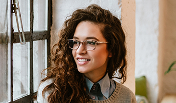 Young woman with glasses and long curly brown hair
