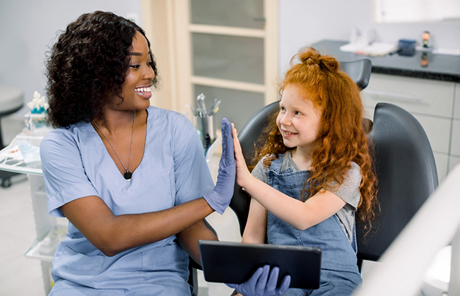 Dentist giving a high five to a girl in the dental chair